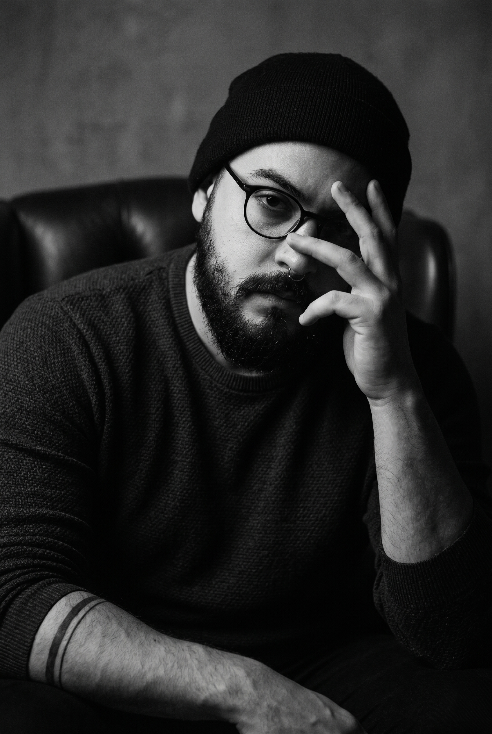 Retrato de Brendown Ferreira em preto e branco, sentado e apoiando o rosto com a mão.